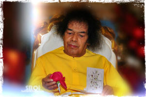 sri-sathya-sai-baba-holding-a-rose-in-his-hand-wearing-yellow-robe.